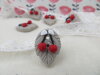 Bouton cerises rouges sur feuille beige